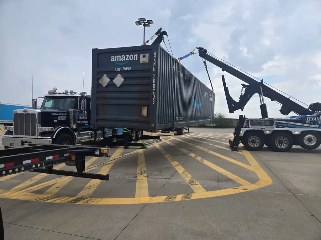 Shipping container suspended from the rotator boom beside the tractor