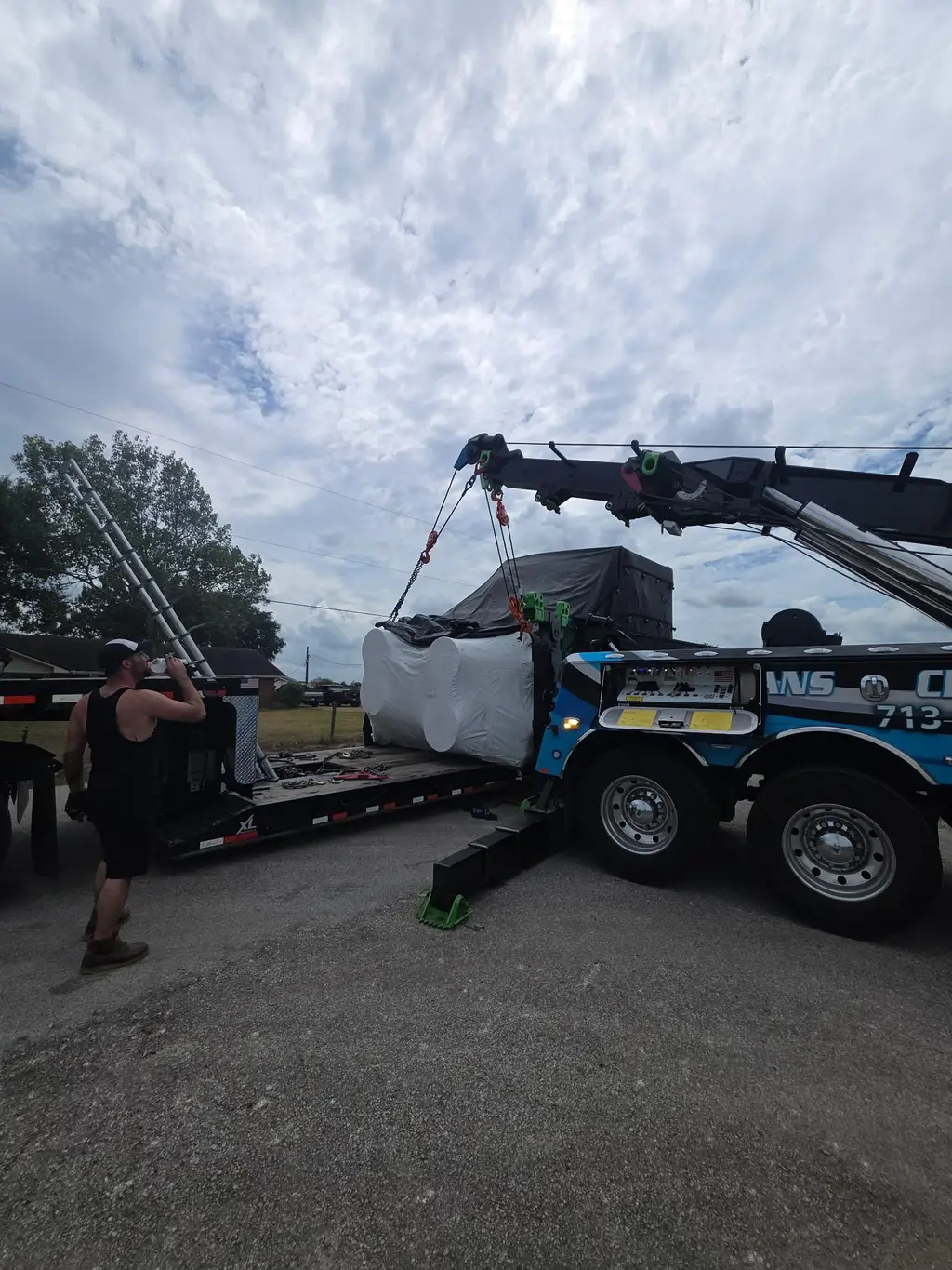 Operator guiding a tarped load as the rotator sets it on a trailer