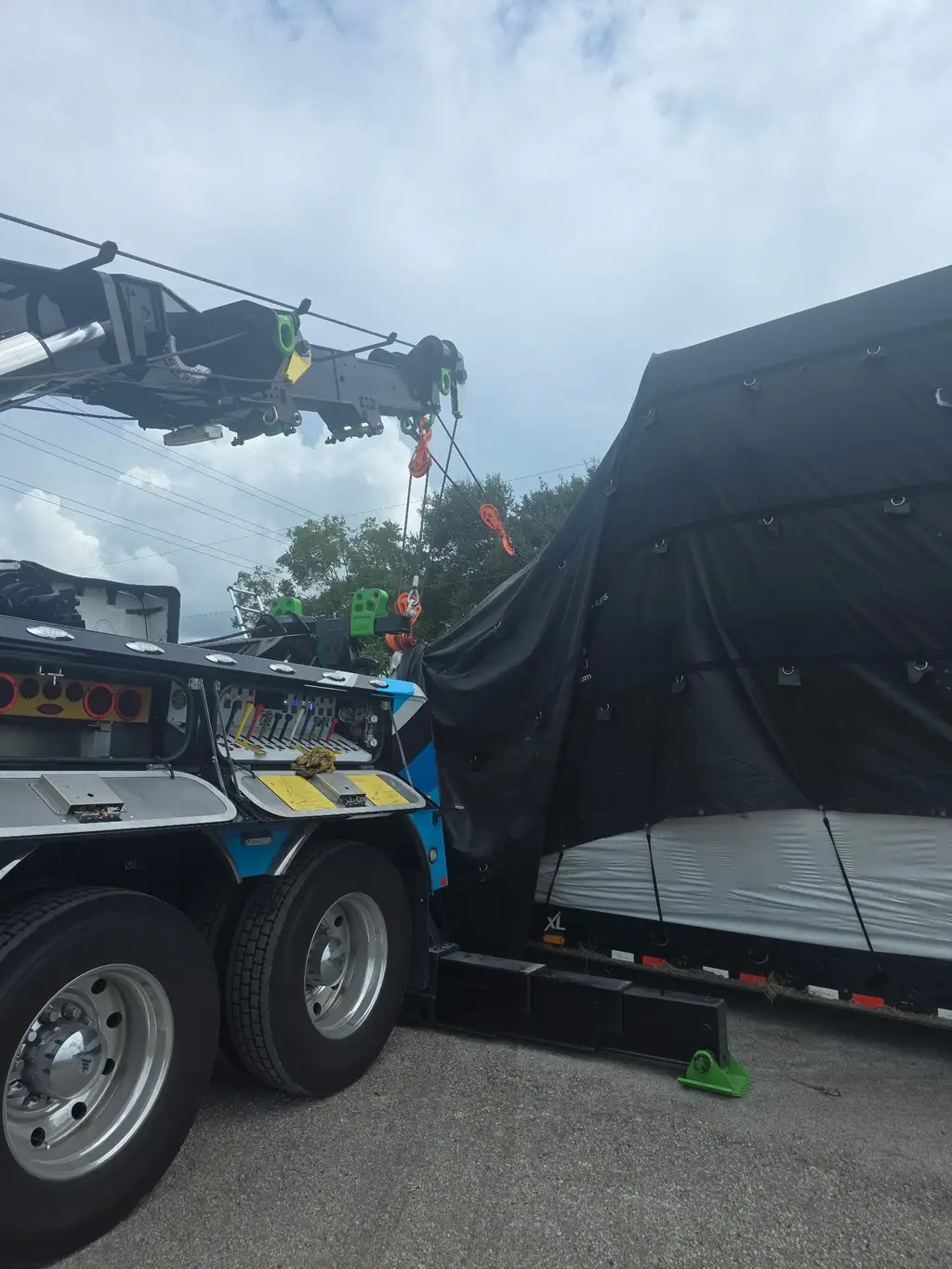 Rotator boom and rigging above a tarped machine on a trailer