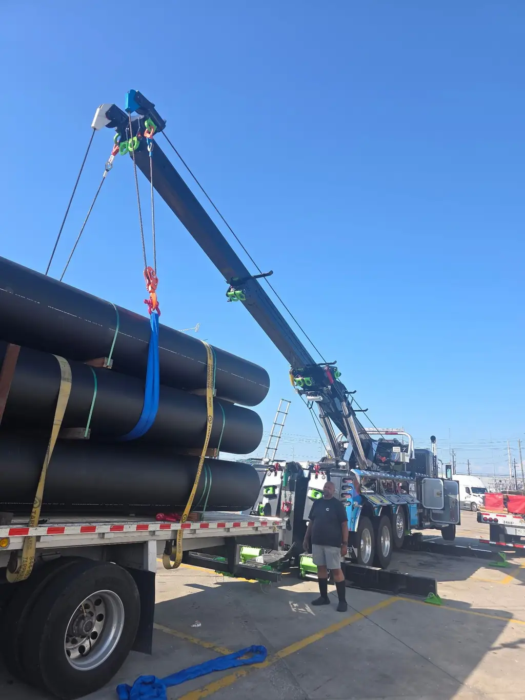 Rotator boom lifting a bundle of large-diameter pipe with slings