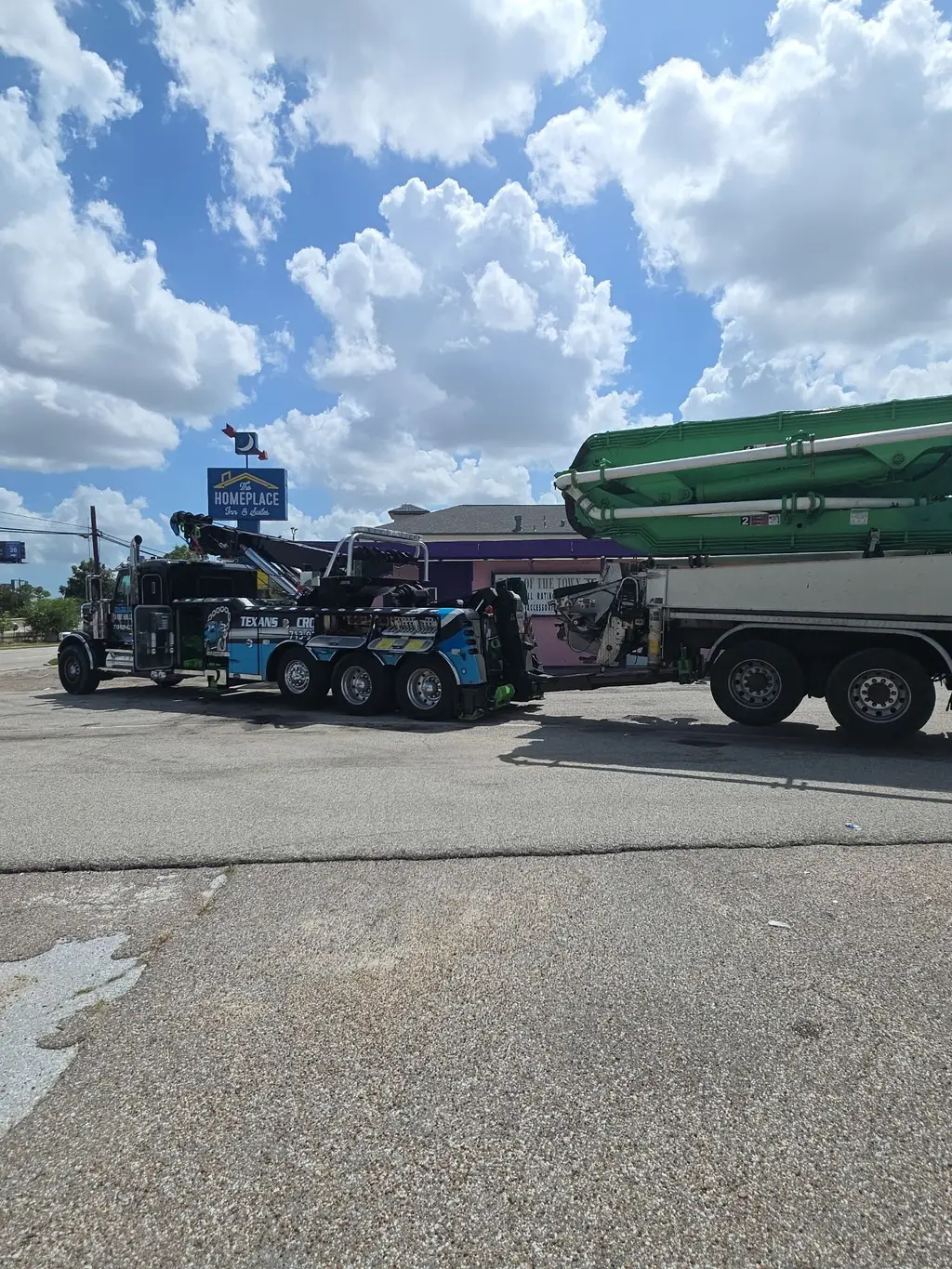 Heavy wrecker hooked to a concrete boom pump truck